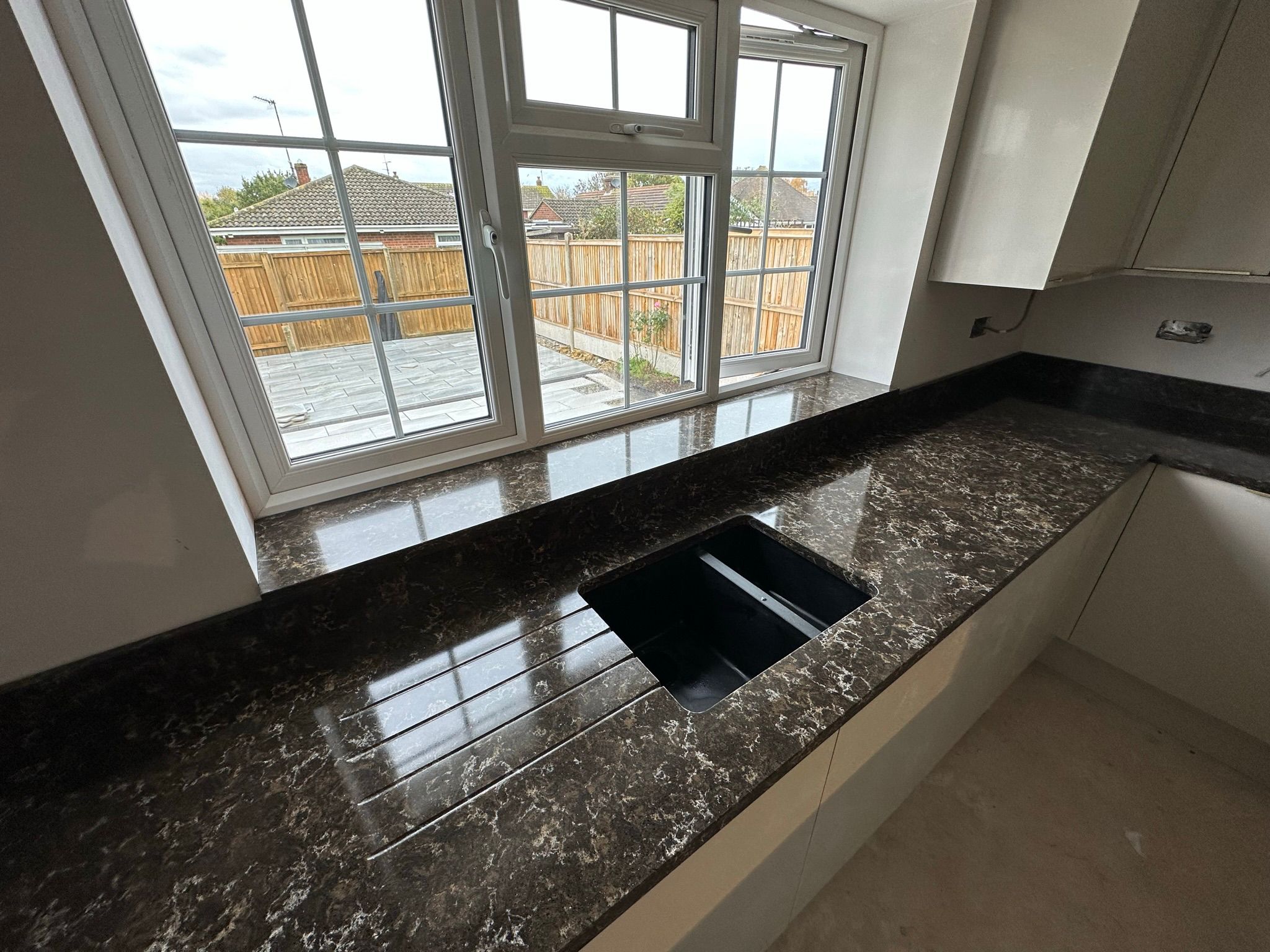 Empty kitchen with large white quartz island under skylights